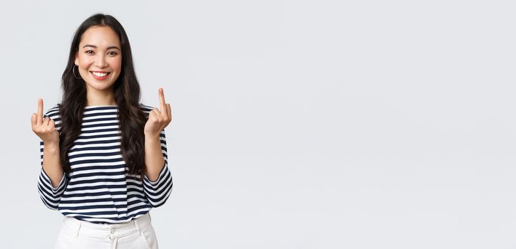 Lifestyle, beauty and fashion, people emotions concept. Unbothered and careless young happy smiling woman dont give a damn, showing middle fingers and feeling good, white background.