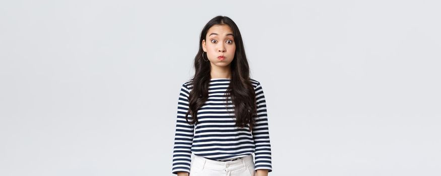 Lifestyle, people emotions and casual concept. Confused cute and puzzled girl pouting, searching for solution, holding breath and staring questioned camera, white background.