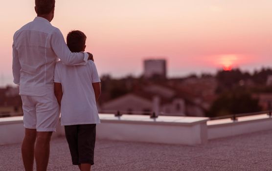 Father and son spend time together on the roof of the house while enjoying the sunset. Selective focus. High-quality photo