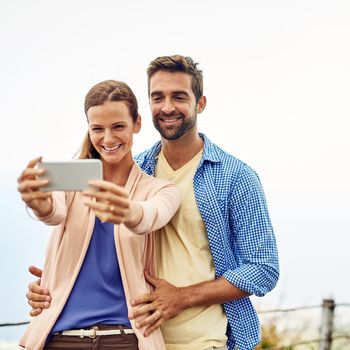 Cropped shot of an affectionate couple taking selfies outside.