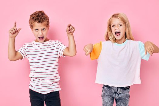 funny children gesturing with their hands playing childhood pink background. High quality photo