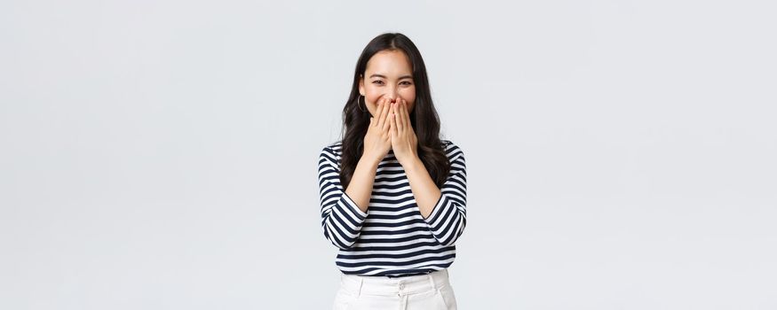 Lifestyle, people emotions and casual concept. Cute silly asian female giggle while gossiping and mocking someone, cover mouth as smiling and laughing carefree.