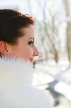 bride posing in the winter forest in a fur coat. Wedding photo session in a snowy Park.