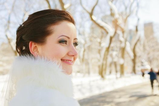 bride posing in the winter forest in a fur coat. Wedding photo session in a snowy Park.