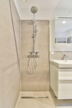 The interior of a bathroom in a modern house with a shower, and a sink under the mirror