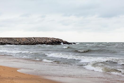 Huge waves raging in the sea and seagulls in the spray of waves. Storm at sea. Birds fly over the waves. Nature, environment, rough weather, danger