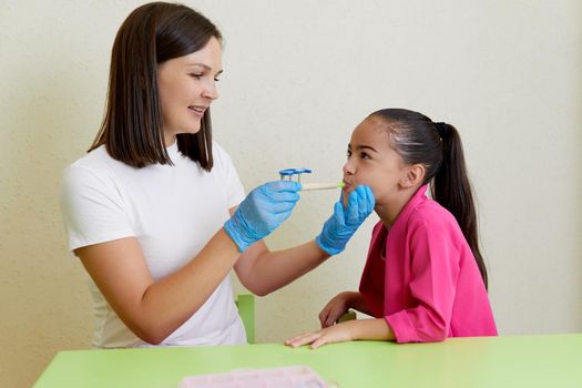 Speech therapist working with little girl in office training correct pronunciation