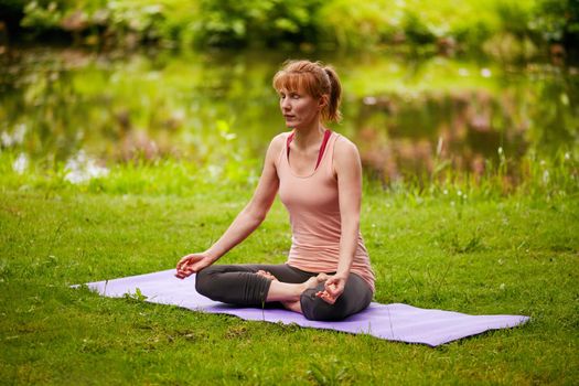 Shot of a woman sitting in the lotus position in the park.