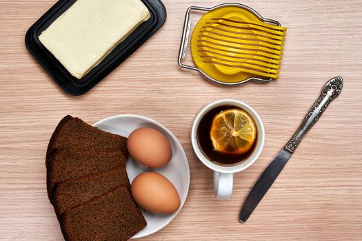 Making a breakfast sandwich, bread and butter and egg with egg on the table. Top view on wooden background
