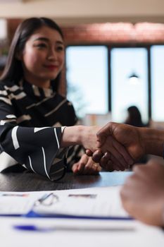 Asian recruiter shaking hands with entrepreneur during interview meeting in startup company office. Businessman discussing cv resume before recruiting woman for hr job. Hiring concept