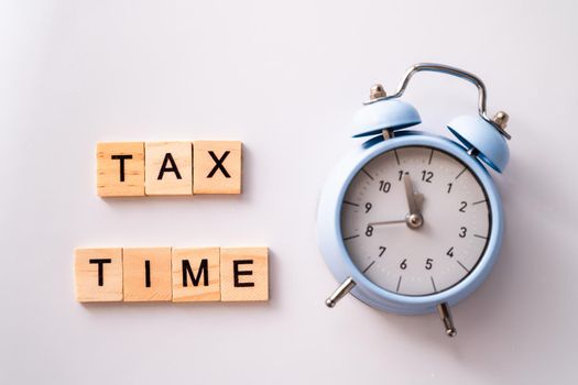 Close-up of alarm clock next to tax time concept on chalkboard.