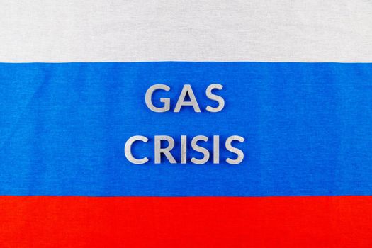 the words gas crisis laid with silver letters over flat full-frame russian flag surface in high angle view
