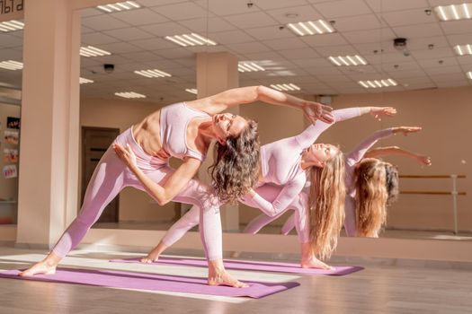 Two beautiful women cook doing yoga, sports together in the gym. Dressed in pink suits. The concept of grace and beauty of the body