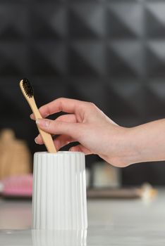 Closeup female hand is holding ecological bamboo brush. woman is preparing going to clean teeth. Tool for oral care. Personal hygiene product concept.