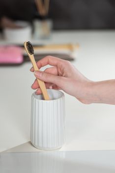 Closeup female hand is holding ecological bamboo brush. woman is preparing going to clean teeth. Tool for oral care. Personal hygiene product concept.