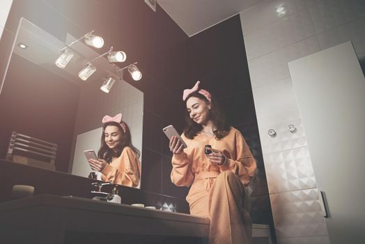 Portrait view of beautiful young woman getting ready in home bathroom. mirror face reflection. Bathroom decorated with a black tiles