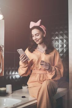 Portrait view of beautiful young woman getting ready in home bathroom. mirror face reflection. Bathroom decorated with a black tiles