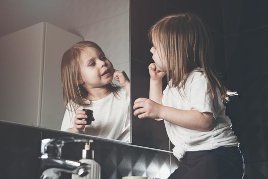 Portrait of beautiful little girl using cream for skincare. . Pretty kid cleansing or moisturize her skin. Teenage and child problems, hygiene, clean and fresh young skin.