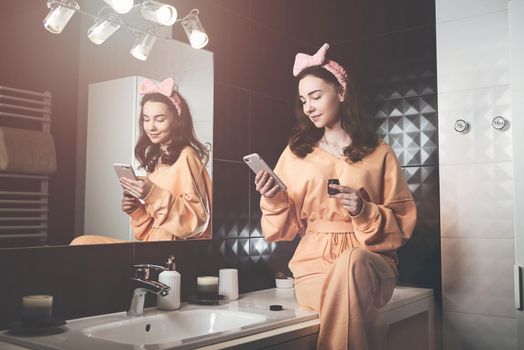 Portrait view of beautiful young woman getting ready in home bathroom. mirror face reflection. Bathroom decorated with a black tiles