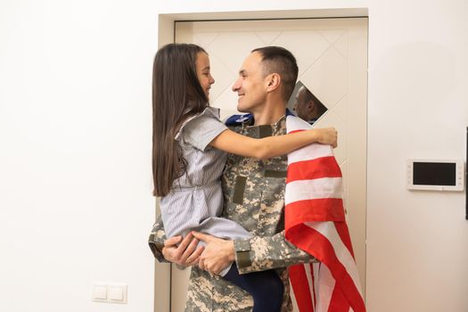 Soldier with flag of USA and his little daughter hugging, space for text.