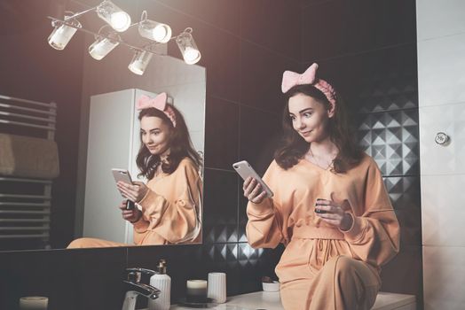 Portrait view of beautiful young woman getting ready in home bathroom. mirror face reflection. Bathroom decorated with a black tiles