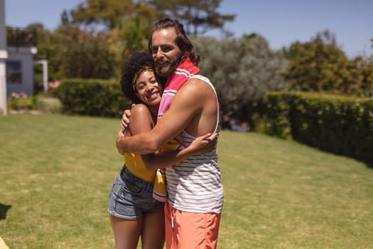 Portrait of two diverse male and female friends embracing at a pool party. Hanging out and relaxing outdoors in summer.