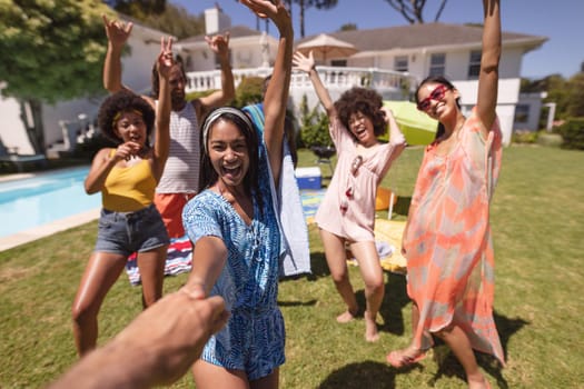 Diverse group of friends having fun and smiling at a pool party. Hanging out and relaxing outdoors in summer.