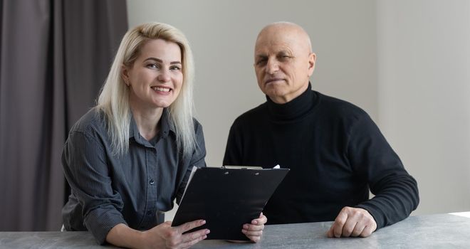 Portrait of female psychiatrist interviewing senior man during therapy session, copy space.