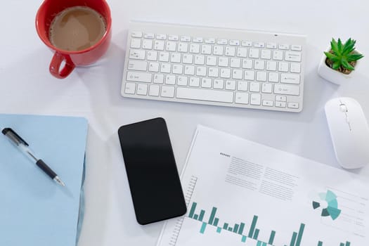 Smartphone computer keyboard paperwork and cup of coffee on desk in office. work and business communication.