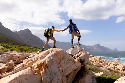 Fit afrcan american couple wearing backpacks hiking on the coast. healthy lifestyle, exercising in nature.