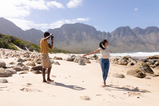 African american couple taking photos on a beach by the sea. healthy lifestyle, leisure in nature.