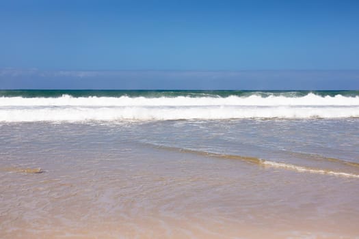 Beautiful beach by the sea and with big waves and golden sand on a sunny day. beautiful view of sunny coast