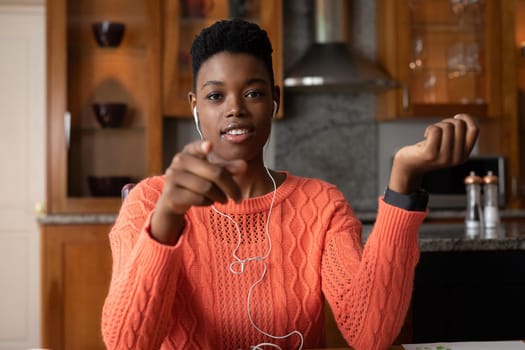 Portrait of african american woman wearing earphones having a videocall while working from home. staying at home in self isolation in quarantine lockdown