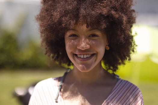 Portrait of mixed race woman looking at camera and smiling. Hanging out and relaxing outdoors in summer.