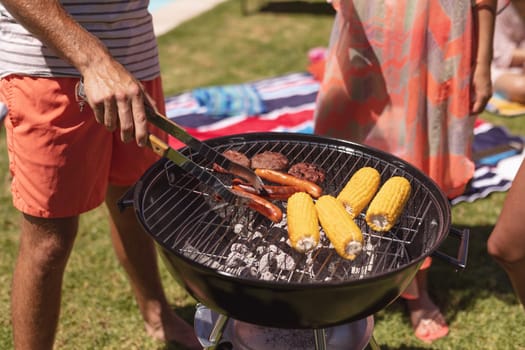 Diverse group of friends having barbecue at a pool party. Hanging out and relaxing outdoors in summer.