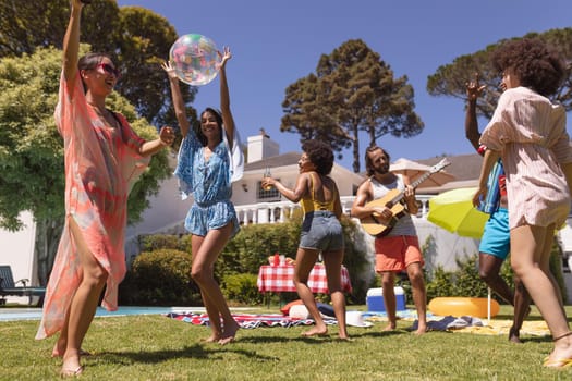 Diverse group of friends dancing and smiling at a pool party. Hanging out and relaxing outdoors in summer.