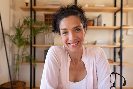 Portrait of smiling caucasian woman sitting at desk, working from home. Staying at home in self isolation during quarantine lockdown.