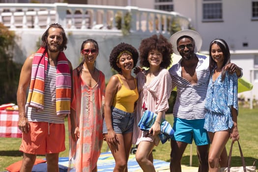 Portrait of diverse group of friends looking at camera and smiling at a pool party. Hanging out and relaxing outdoors in summer.