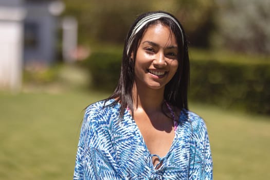 Portrait of mixed race woman looking at camera and smiling. Hanging out and relaxing outdoors in summer.