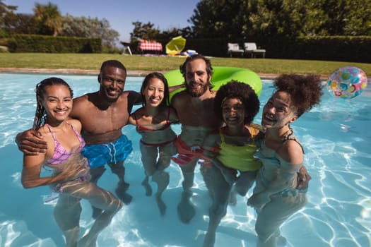 Portrait of diverse group of friends having fun in swimming pool. hanging out and relaxing outdoors in summer.