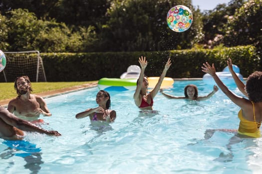 Diverse group of friends having fun in swimming pool. Hanging out and relaxing outdoors in summer.