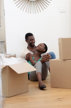 African american couple moving house unpacking sitting on floor and embracing. staying at home in isolation during quarantine lockdown.