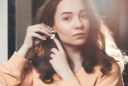 close up of beautiful young woman puts on heart shaped earrings