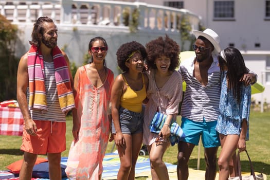 Diverse group of friends embracing and smiling at a pool party. Hanging out and relaxing outdoors in summer.