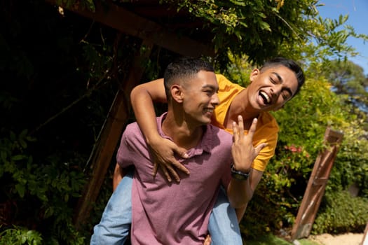 Diverse gay male couple spending time in garden embracing and smiling. staying at home in isolation during quarantine lockdown.