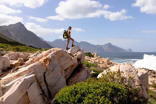 Fit afrcan american woman wearing backpack hiking on the coast. healthy lifestyle, exercising in nature.