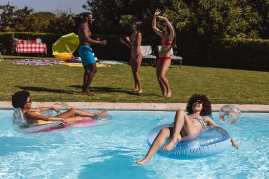 Diverse group of friends having fun and dancing at a pool party. Hanging out and relaxing outdoors in summer.