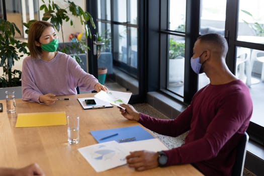 Two diverse business people working in creative office. two people in a meeting discussing work. social distancing protection hygiene in workplace during covid 19 pandemic.