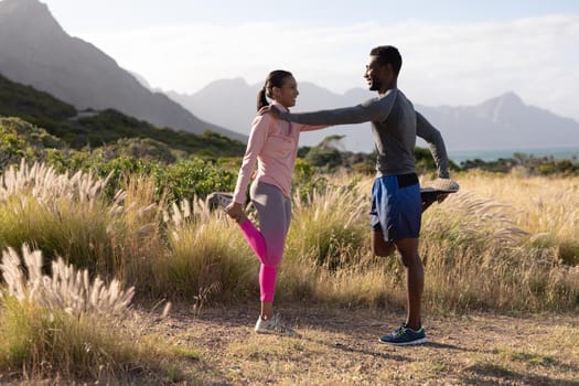 Fit african american couple in sportswear stretching in tall grass. healthy lifestyle, exercising in nature.