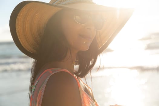Portrait of smiling mixed race woman on beach holiday. healthy outdoor leisure time by the sea.